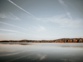 A body of water with rocky land in the distance and a blue sky