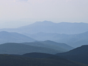 Dark green hills rolling into the distance with fog covering the background hills